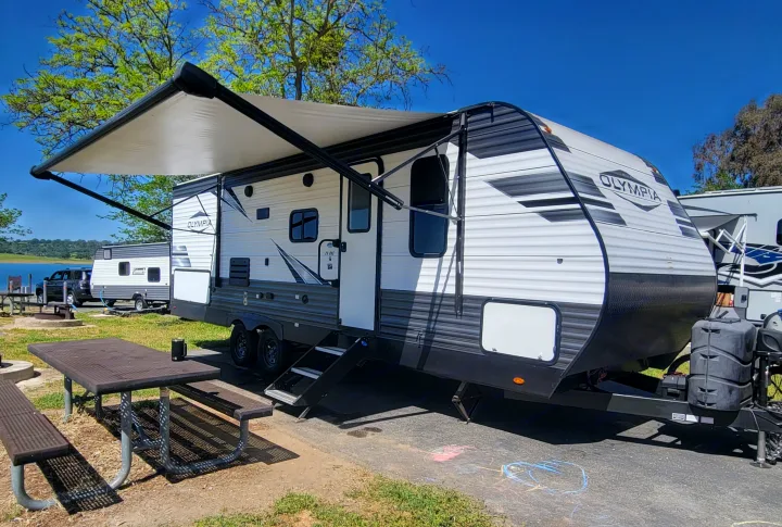 Spacious Olympia RV rental at a scenic lakeside campsite with an extended awning and picnic table.. Highland Ridge RV Olympia 2022