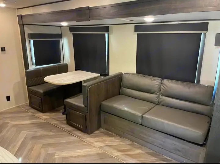 Spacious RV rental interior with comfy dinette, table, and sofa. Modern design for comfortable travel.. Highland Ridge RV Olympia 2022