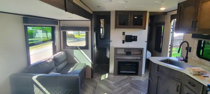 Spacious rv rental interior featuring a modern living area with a sofa, kitchen, and entertainment center with fireplace.. Highland Ridge RV Olympia 2022
