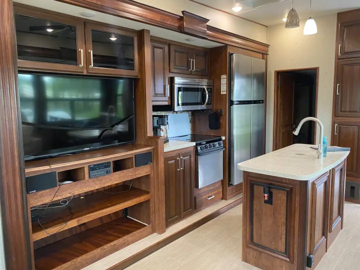 Spacious RV rental interior with a well-equipped kitchen island, entertainment center, and modern appliances.. Keystone RV Avalanche 2017