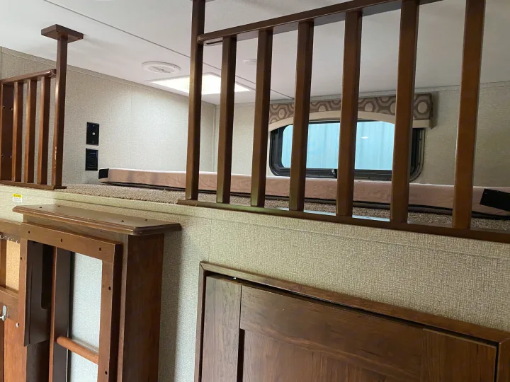 An rv rental's cozy loft bed area featuring a wooden safety railing, carpeted floor, and wall outlets.. Keystone RV Avalanche 2017