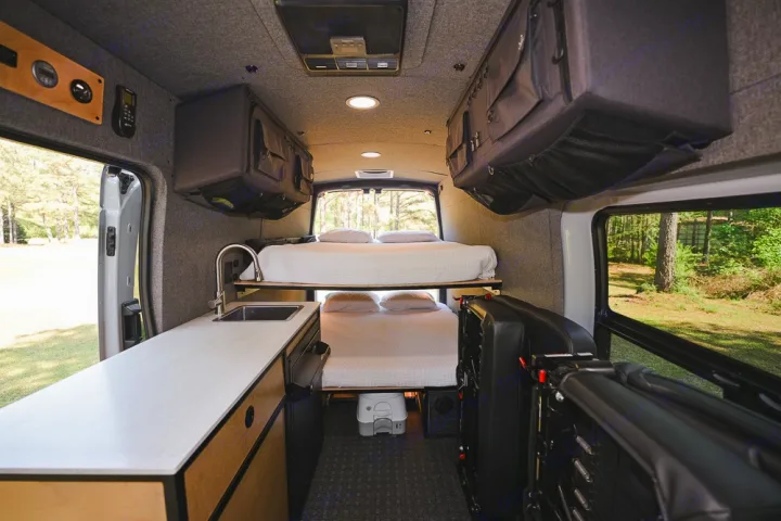This RV rental interior offers bunk beds, a kitchenette with a sink, and ample overhead storage for your next adventure.. Ford Transit 250 2023