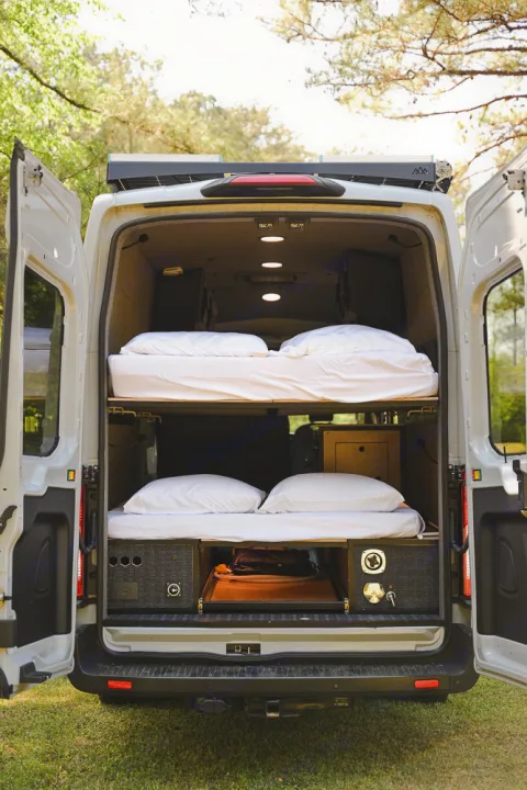 RV rental van's organized interior features stacked bunk beds and lower storage for travel.. Ford Transit 250 2023