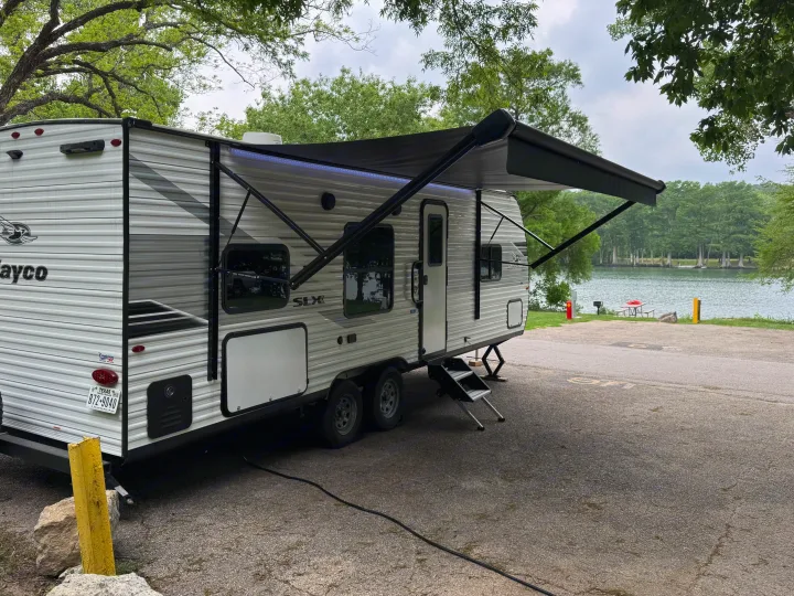 Lakeside RV rental travel trailer set up with awning extended at a scenic campsite.. Jayco 260BH 2025