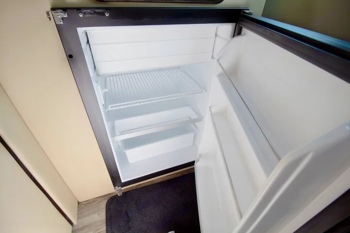 Clean, empty compact refrigerator inside an RV rental, ready for your travel snacks and drinks. Perfect for road trips.. Ultimate Toys Ultimate Commuter 144 2022