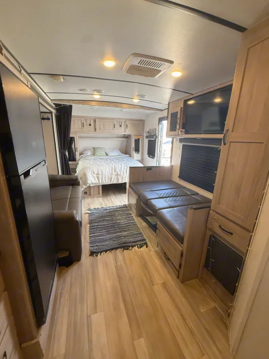 This RV rental interior offers a comfy bed, convertible dinette, lounge, and fridge. Ideal travel trailer for your next adventure.. Forest River Coachmen Northern Spirit Ultra Lite 2023