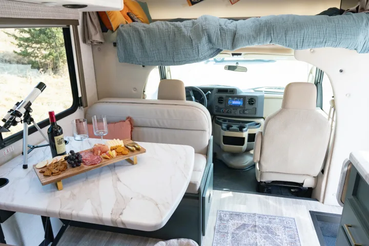 Cozy RV rental interior: charcuterie, wine, telescope, comfy bunk, and front cab. Perfect for your next adventure!. Thor Motor Coach Eddie Bauer 21EBF 2025
