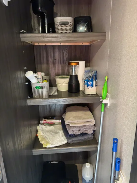 Inside an RV rental: Compact and organized cabinet with essentials, cleaning tools, and a coffee station.. Forest River Shasta 2020