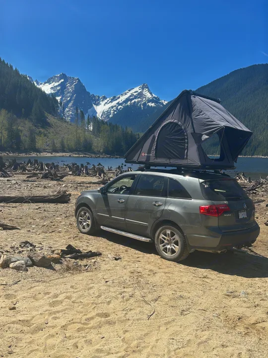 Gray Acura SUV with Galaxy rooftop tent, deployed by a lake with mountains. A unique rv rental option for camping.. Other Other 2007