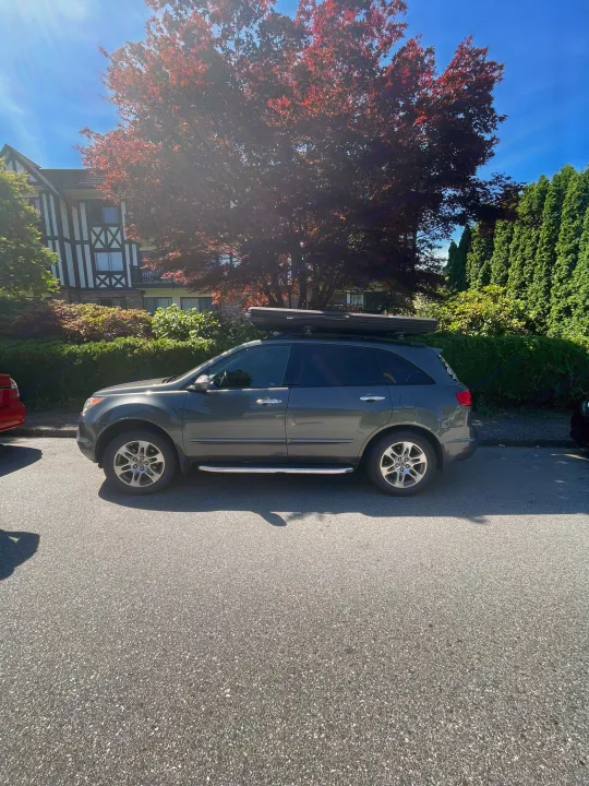 Dark grey SUV with roof cargo box parked on a sunny street, useful for trips like an RV rental. Tudor-style house visible.. Other Other 2007