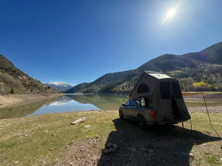 A truck with a rooftop tent is set up for camping beside a calm mountain lake, an adventurous **RV rental** alternative.. Ford Ranger 2300 Cc 2022