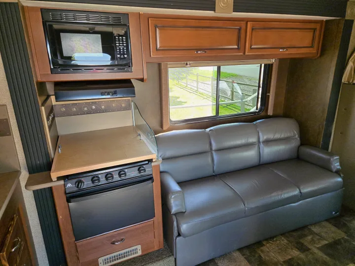 Step inside this RV rental! Features a compact kitchen with microwave, oven, and a comfy sofa with a window view.. Tioga Ranger 2014