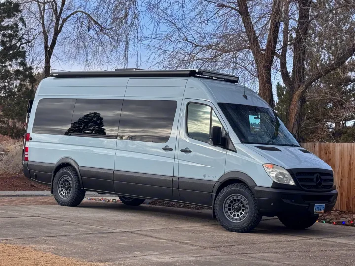 A light gray Mercedes Sprinter **RV rental** sits parked, an adventure-ready conversion van.. Mercedes-Benz Sprinter RV Motorhome Campervan 2012