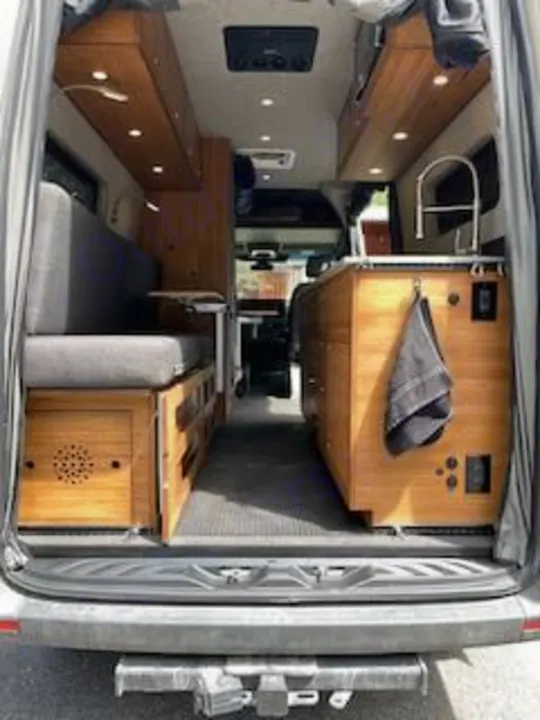 Inside this modern RV rental, a camper van conversion reveals a kitchen on the right, seating on the left, and overhead storage.. Mercedes-Benz Sprinter RV Motorhome Campervan 2020
