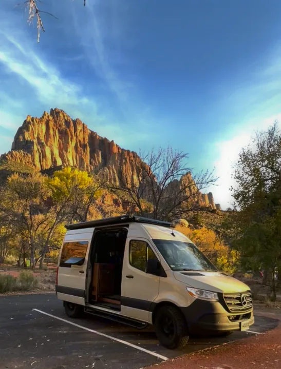 Light-colored Sprinter camper van (RV rental) parked in golden light, facing majestic mountains. Ready for adventure.. Mercedes-Benz Sprinter RV Motorhome Campervan 2020