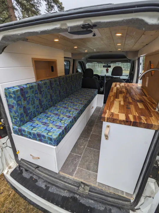 Custom campervan interior with colorful seating, wood counter, and ceiling lights, ideal for an rv rental adventure.. Dodge Sprinter Van 2015