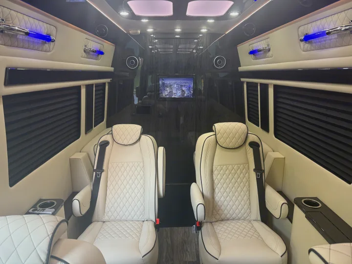 Inside a luxury RV rental: cream quilted seats, ambient blue lights, and a TV, designed for ultimate comfort.. Mercedes-Benz Sprinter 2025