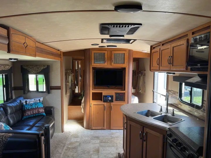 RV rental interior showcasing the kitchen, living area with sofa, and built-in entertainment center.. Crossroads RV Sunset Trail Super Lite 2017