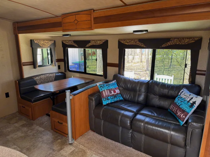 Cozy RV rental interior with a dinette, sofa, and scenic windows, offering a comfortable travel living space.. Crossroads RV Sunset Trail Super Lite 2017