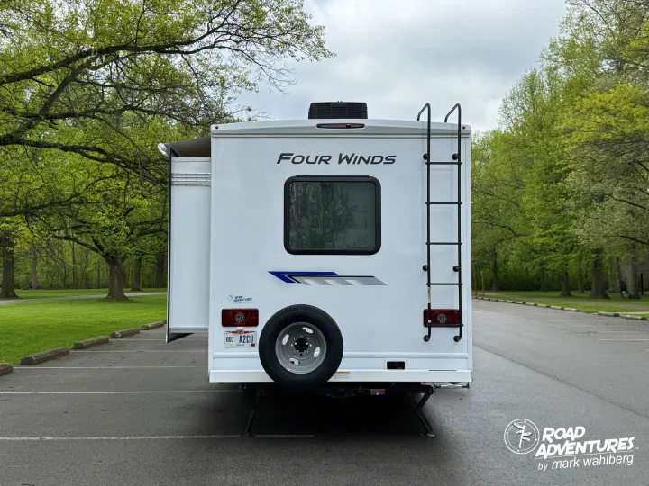 A white Four Winds rv rental, complete with an Ohio dealer plate, parked in a lush green park setting, ready for road adventures.. Thor Motor Coach Four Winds 2026
