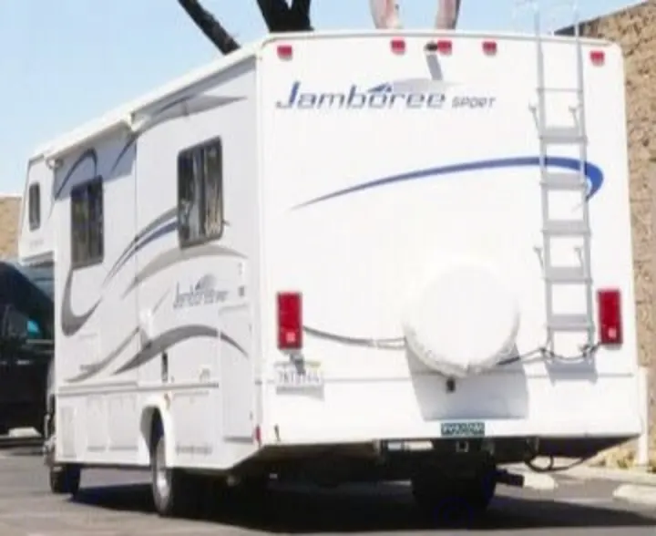 A white Jamboree Sport motorhome, possibly an rv rental, ready for travel. The rear features a ladder and covered spare tire.. Jamboree Sport 2010