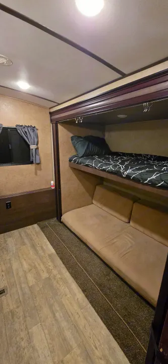 Explore this RV rental's cozy interior, featuring bunk beds, window, and practical flooring. Ideal for family adventures.. Forest River Surveyor 2016