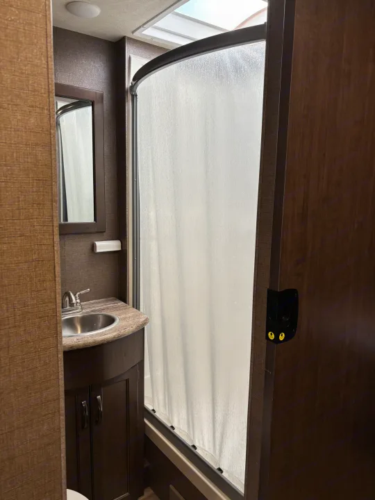 RV rental bathroom features: sink, mirror, curved shower stall, and vanity. Ready for your adventure.. Thor A.C.E. 2018