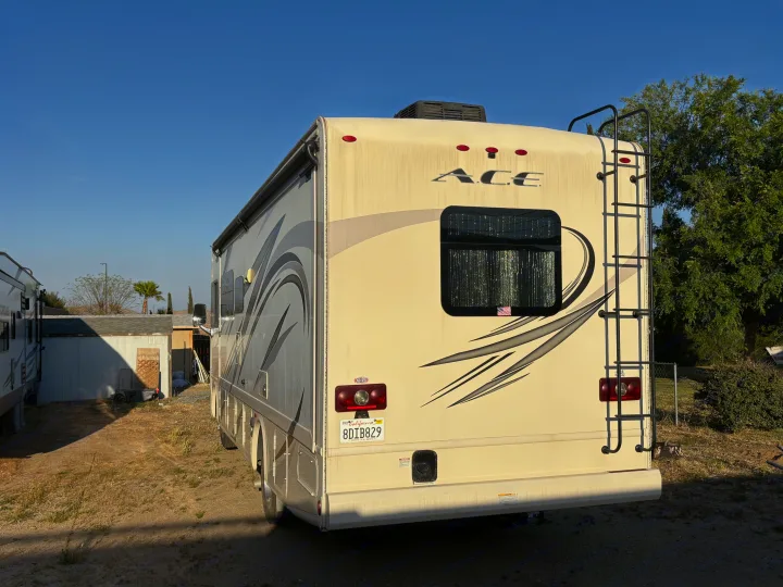 Back of a cream Thor ACE motorhome, an RV rental option, with a ladder and California license plate visible.. Thor A.C.E. 2018