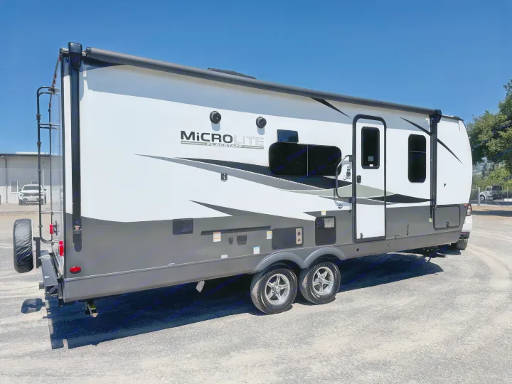 A sleek white and grey Micro Lite Flagstaff travel trailer, equipped with an awning, ideal for rv rental and outdoor adventures.. Flagstaff Micro Lite 25DBH 2025