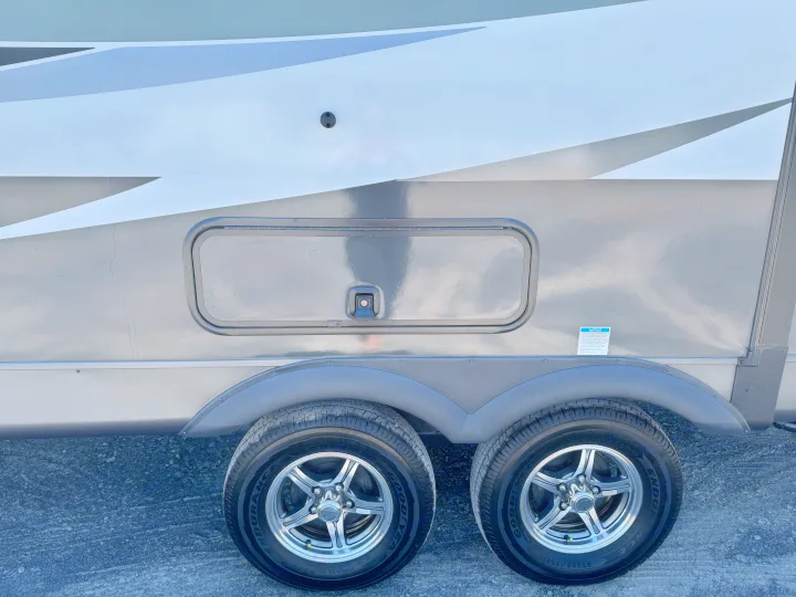 An RV rental side view with a gray/white exterior, a storage compartment, and two Goodyear tires on silver rims.. Flagstaff Micro Lite 25DBH 2025