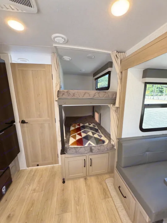 RV rental interior: cozy bunk beds, light wood floors, and seating area with a view. Ideal for your next adventure.. Flagstaff Micro Lite 25DBH 2025
