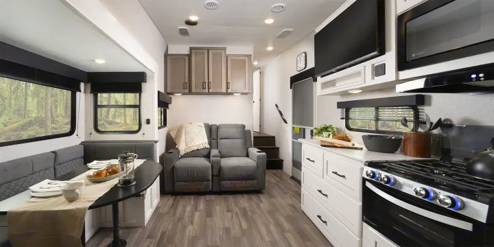 Experience comfort in this RV rental: a modern interior with kitchen, recliners, and dining booth overlooking a forest.. Jayco Eagle Super Lite 2025