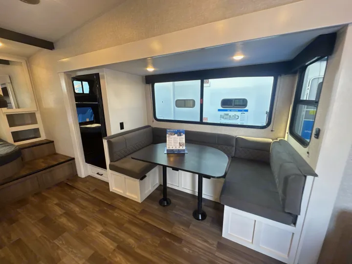 RV rental: Dinette with U-shaped seating, dark table, and large windows. Bunk bed area with steps visible on the left.. Jayco Eagle Super Lite 2025