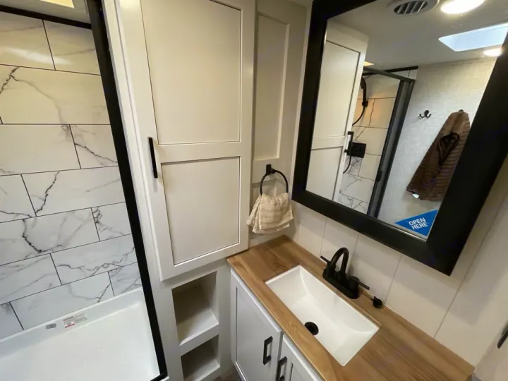 Modern RV rental bathroom showcasing a stylish vanity, sleek black fixtures, and a white marble-look shower.. Jayco Eagle Super Lite 2025