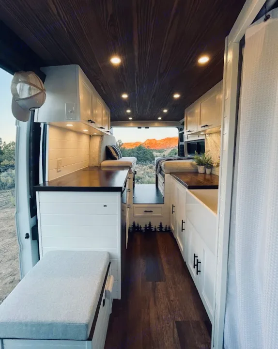 Step inside this cozy rv rental van: a bright, modern interior with white cabinets, wood accents, and desert views.. Dodge Ram 1500 2019