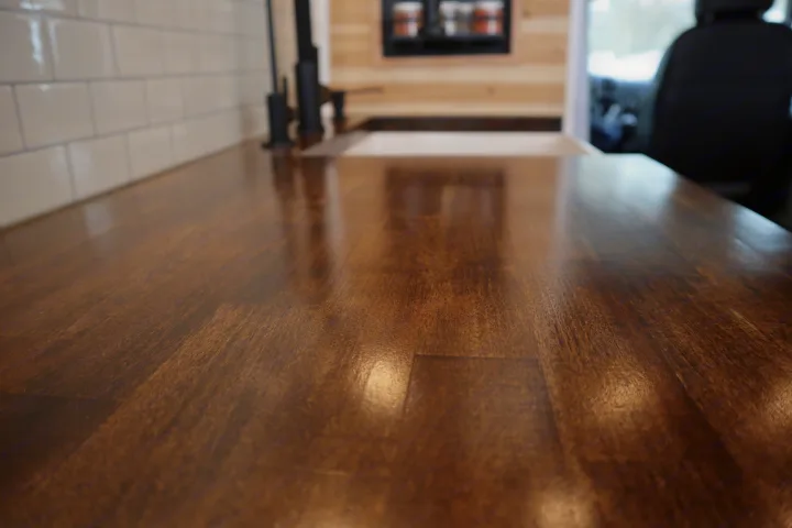 RV rental kitchen: A close-up of a rich wooden countertop, white subway tile, and modern black faucet in a sleek interior.. Dodge Ram 1500 2019