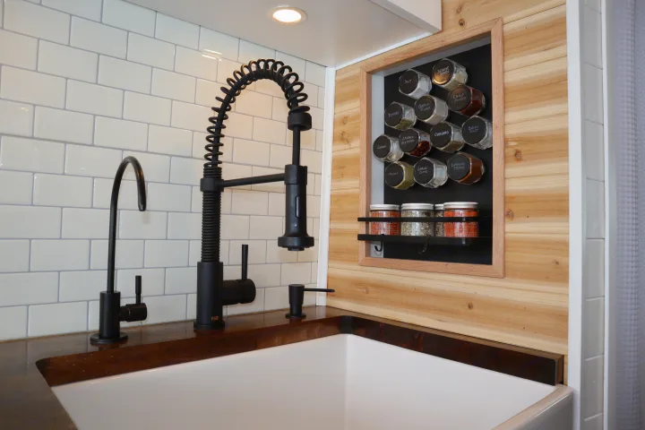 Modern RV rental kitchen with a sleek black faucet, white subway tile, and a clever built-in magnetic spice rack.. Dodge Ram 1500 2019