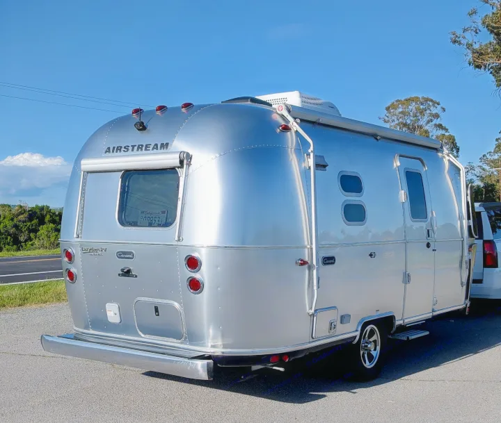 This silver Airstream RV rental is ready for a scenic road trip, gleaming under a clear blue sky.. Airstream Caravel 2023