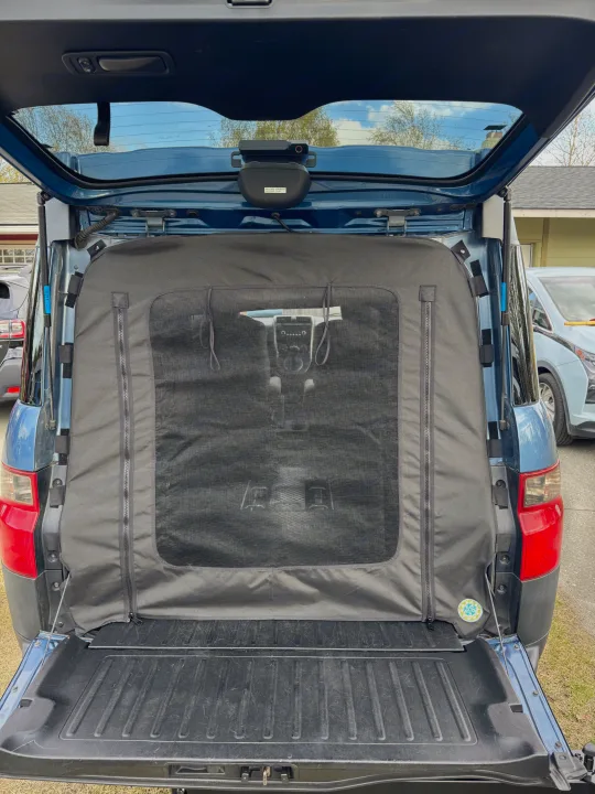 Open car trunk with a mesh screen/pet barrier, ideal for camping or travel, perfect for an RV rental adventure.. Honda Element Ecamper 2008