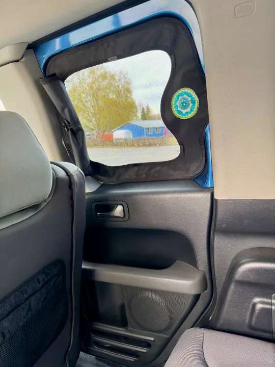 Car interior from an RV rental, featuring a custom mesh window screen with a colorful patch. Ideal for travel & privacy.. Honda Element Ecamper 2008