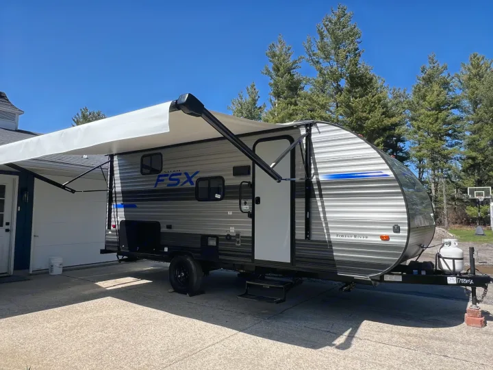 This RV rental, a grey Forest River Salem FSX travel trailer, is parked with its awning extended on a sunny day.. Forest River Salem FSX 2021