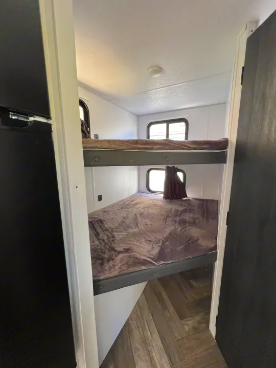 Spacious RV rental features twin bunk beds with soft blankets & windows, providing cozy sleeping quarters.. Forest River Salem FSX 2021