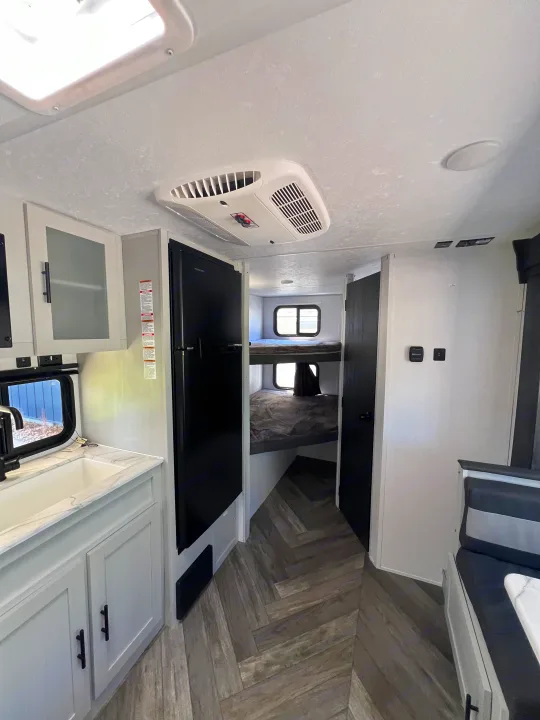 Modern RV rental interior, showcasing a well-equipped kitchen, spacious fridge, and cozy bunk beds. Ideal for family adventures.. Forest River Salem FSX 2021
