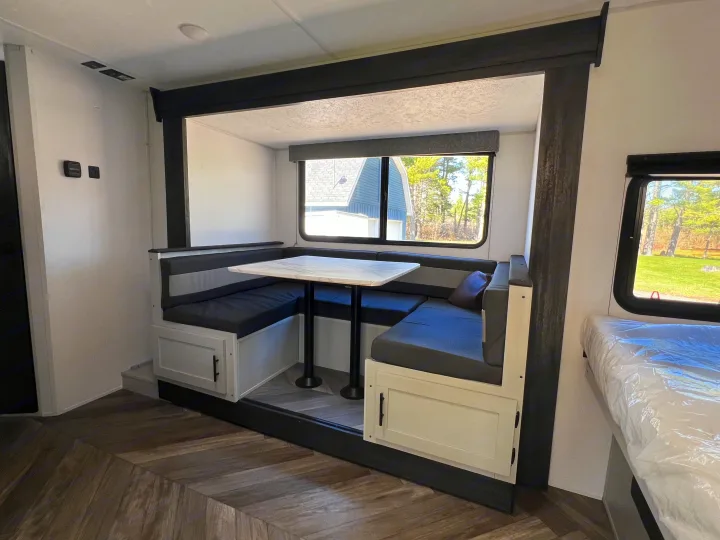 Inside a modern RV rental: a dark grey U-shaped dinette with a white table and storage. Ready for your journey.. Forest River Salem FSX 2021