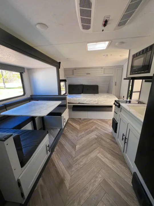 Inside a sleek RV rental: comfortable dinette, compact kitchen, and inviting bed area for your travels.. Forest River Salem FSX 2021