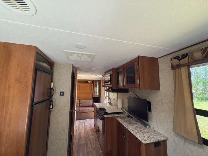 Bright RV rental interior showing kitchen with sink, stovetop, microwave, fridge, and living area. Modern and clean.. Tracer Tracer Air 2017