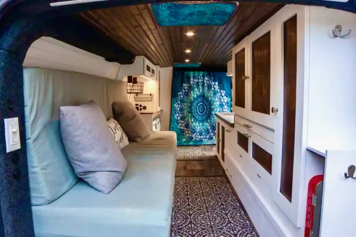Explore this cozy RV rental interior: comfortable bed, organized kitchen, and stylish cabinets. Perfect for your next adventure.. Chevrolet Express 3500 2012