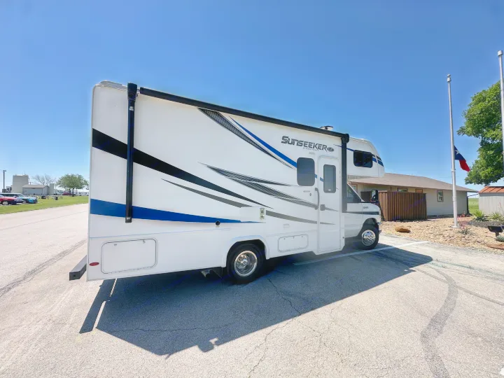 White Sunseeker by Forest River rv rental, featuring blue & black graphics, parked on pavement on a clear day.. Forest River Sunseeker LE 2021