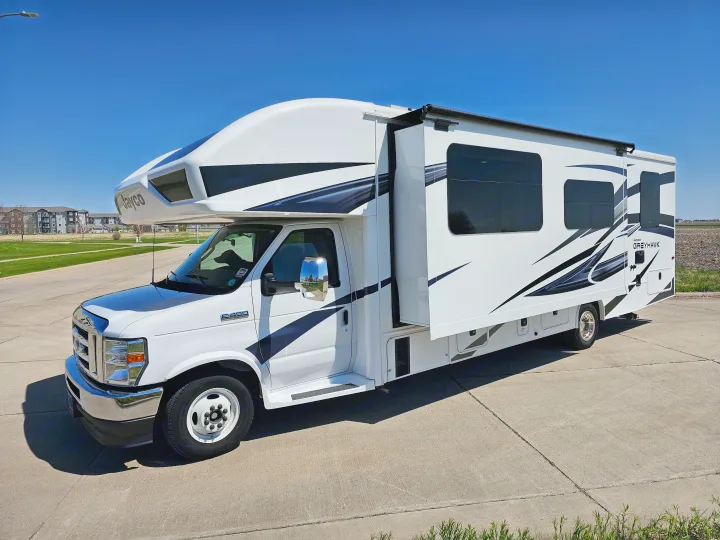 This white Class C RV rental, a Jayco Greyhawk motorhome, is ready for travel. Parked on sunny concrete.. Jayco Greyhawk 2023