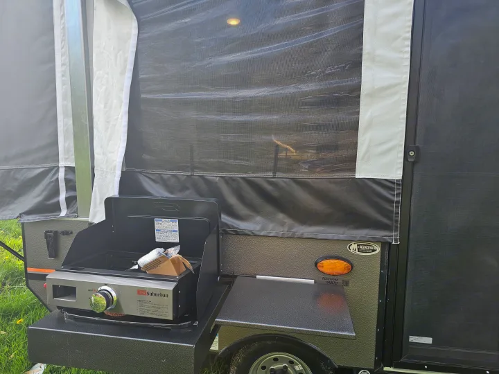 An RV rental Rockwood 1940LTD pop-up camper with an attached Suburban grill for outdoor cooking.. Forest River Rockwood LTD 2024